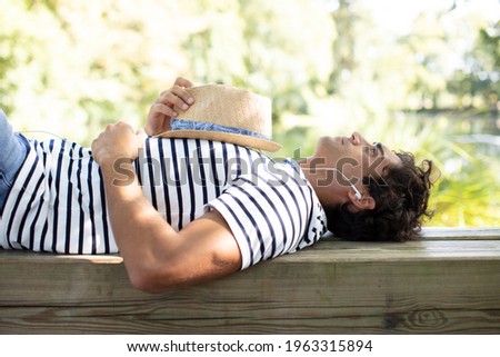 man relaxing outdoors listening to earphones