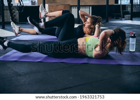 Young woman and her coach performing the bicycle crunches Royalty-Free Stock Photo #1963321753
