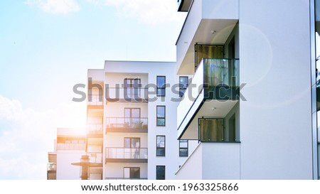 Detail of new luxury house and home complex. Glass surface with sunlight. Rising sun on the horizon. Part of modern residential apartment with flat building exterior.  Velvia graphic filter. Royalty-Free Stock Photo #1963325866