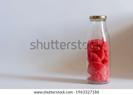 Glass bottle and marmalade in the form of red lips. On white background. Place for text.
