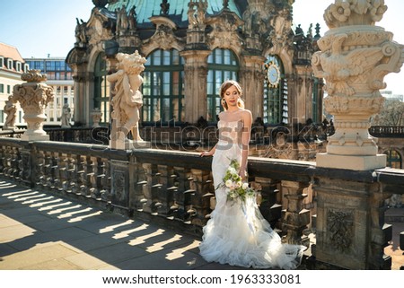 A bride in a white dress with a bouquet on a wedding walk at the famous Baroque Zwinger Palace in Dresden, Saxony, Germany.