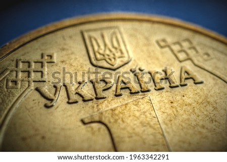Translation of the inscription: Ukraine. Fragment of the Ukrainian coin in 1 hryvnia. Aged showy illustration on the theme of economy and public finance. Vignetting. Focus on the name of the country