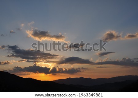 High resolution shot of sun behind clouds during sunset of hilly area of Himachal Pradesh, Beautiful view of colorful sunset - Stock Photo 