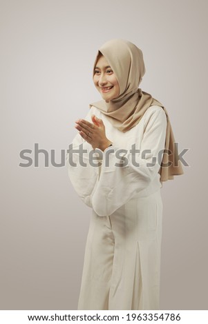 Beautiful Asian Muslilm woman wearing hijab with greeting gesture on ramadhan isolated on white background