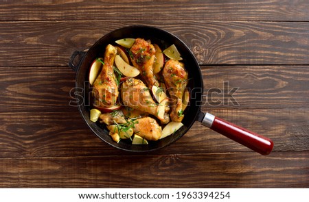 Chicken drumsticks baked with apples and herbs on wooden background with free text space. Top view, flat lay