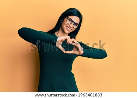 Young caucasian woman wearing casual clothes and glasses smiling in love doing heart symbol shape with hands. romantic concept. 