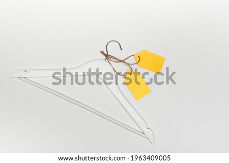 Wooden coat hanger with yellow paper labels on white background. Label blank mockup template. Clothing tag.