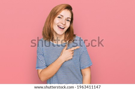 Young caucasian woman wearing casual clothes cheerful with a smile of face pointing with hand and finger up to the side with happy and natural expression on face 