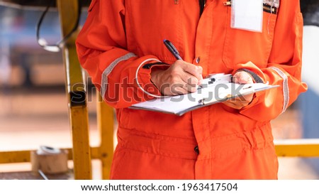 Action of safety officer is wirtinng and check on checklist document during safety audit and inspection at drilling site operation. Industrial expertise occupation photo. Royalty-Free Stock Photo #1963417504