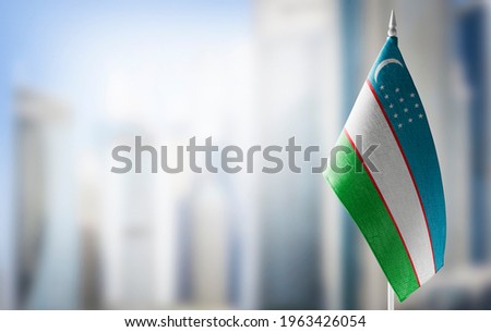 A small flag of Uzbekistan on the background of a blurred background Royalty-Free Stock Photo #1963426054