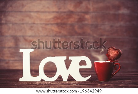 Cup of coffee and word Love on wooden table.