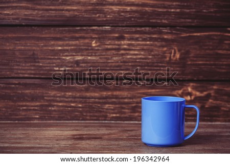 Cup on wooden table and with wood on background