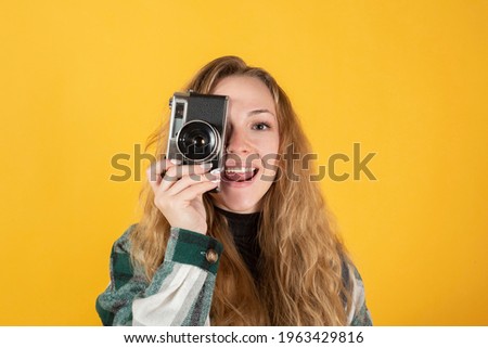 pretty blonde woman with a camera, on yellow background