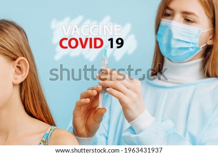 Female doctor vaccinates little girl on blue background, close up, coronavirus vaccination concept