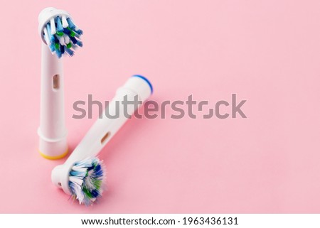 New and used spare brush heads for electric toothbrush. Closeup, pink background. 