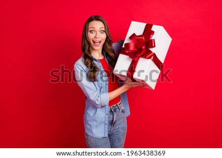 Photo of funky impressed young lady dressed denim outfit holding big bow present box isolated red color background