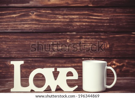 White cup and wooden word Love on table.