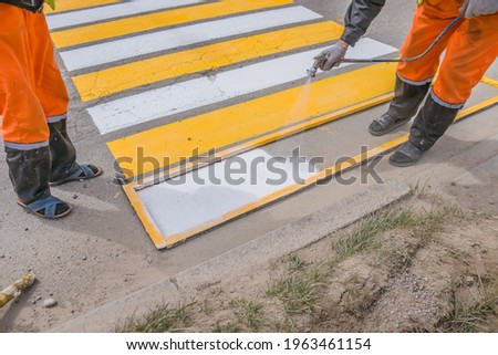 Road works. Paint application on asphalt at a pedestrian crossing.