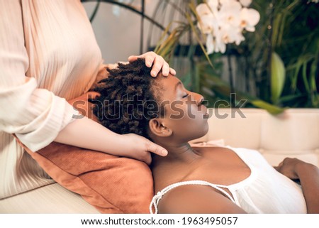 Young healer working woith a dark-skinned patient in ayurvedic salon Royalty-Free Stock Photo #1963495057