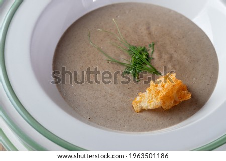mushroom cream soup with herbs and breadcrumbs (croutons) in a white plate. low-depth-of-field photos with blurred elements