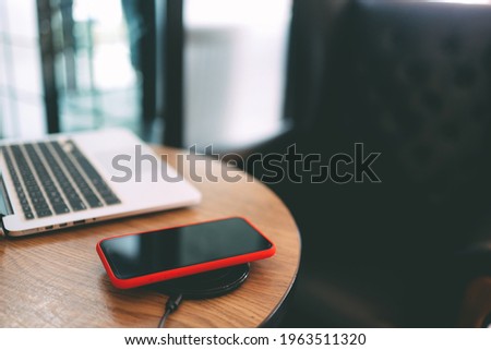 Charging mobile phone battery with wireless device in the table. Smartphone charging on a charging pad. Mobile phone near wireless charger