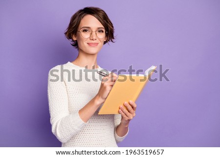 Photo portrait of smart girl writing in organizer wearing glasses smiling isolated on pastel purple color background