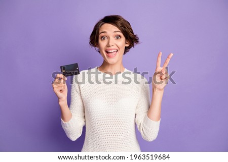 Photo portrait of brunette keeping debit card showing v-sign gesture isolated on pastel violet color background
