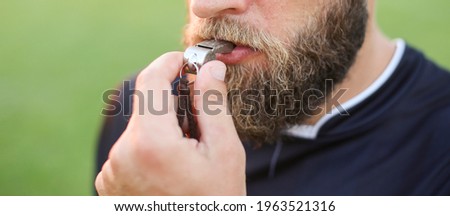 Close up of a football referee's whistle in his mouth Royalty-Free Stock Photo #1963521316