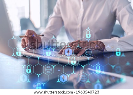 A woman programmer is typing a code on computer to protect a cyber security from hacker attacks and save clients confidential data. Padlock Hologram icons over the typing hands. Formal wear.