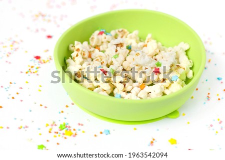 close-up. popcorn in a green children's plate. color picture with colored sprinkles. food, snack