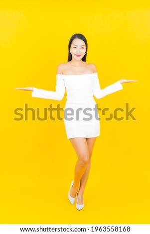 Portrait beautiful young business asian woman with smile and action yellow background
