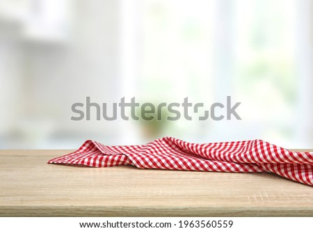 Empty table decorated with red checkered towel food advertisement display. Tabletop with empty space. Picnic table on wooden deck,blurred backdrop. Promotion background.
