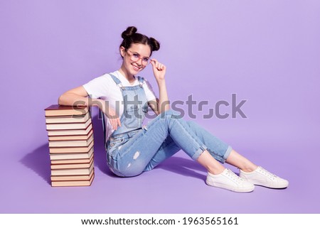 Full size photo of charming cheerful lady sit on floor hand touch glasses isolated on violet color background