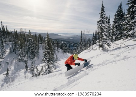 Snowboarder freerider climbing the mountain in  winter sunny day