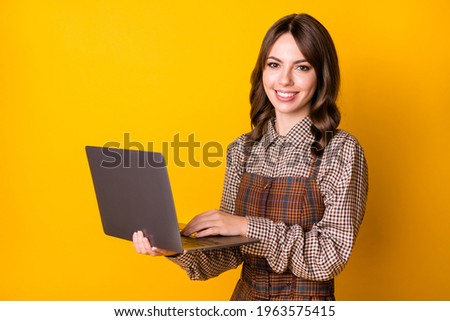 Photo of optimistic brunette lady with laptop wear brown shirt isolated on vivid yellow color background