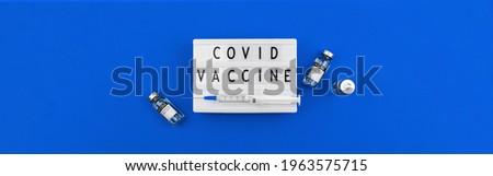Covid vaccine banner concept with text, lettering on the lightbox, hospital blue background with vaccine vials, copy space