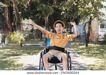 Asian Disabled child on wheelchair is playing, learning and exercise in the outdoor city park like other people with family, Lifestyle in the education age, Happy disability kid with nature concept.