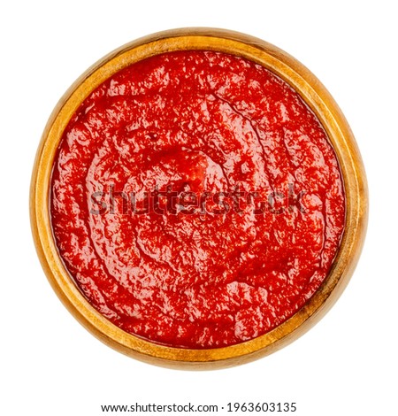 Homemade tomato ketchup in a wooden bowl. Red sweet and tangy table condiment, made from tomato paste, sugar, vinegar and seasonings, served to fried or greasy dishes. Close-up from above, food photo. Royalty-Free Stock Photo #1963603135