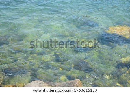 Abstract photo of lake background with greenish and blue water and stones with small waves in zoom photo