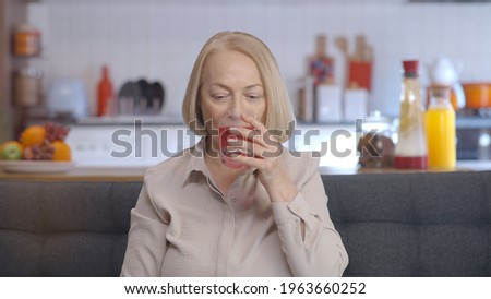The old lady with blond glasses throws an effervescent tablet in a glass of water and watches it dissolve in water. Taking medication supplements. Portrait of people using medication.