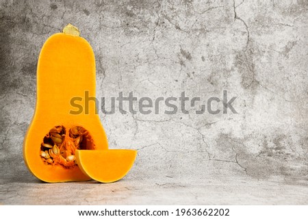 Butternut squash with slices beside against concrete background. Healthy food.Print for stand for plates. Kitchen picture