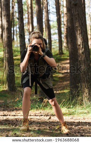 Woman hiker taking photos using  modern mirrorless camera in green forest