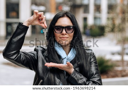 Young brunette girl in sunglasses happily demonstrates the keys to her new home