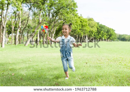 Cheerful Asian little girl playing and running alone in the park with happy and smile