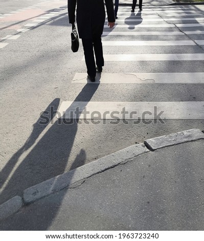Asphalt texture background with legs and shadows citizens crossing road on pedestrian zebra