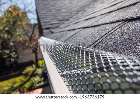 Plastic guard over gutter on a roof  Royalty-Free Stock Photo #1963736179