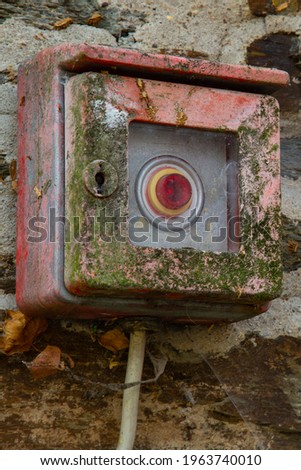 Old fire alarm box unneeded since a long time with lichen and rust