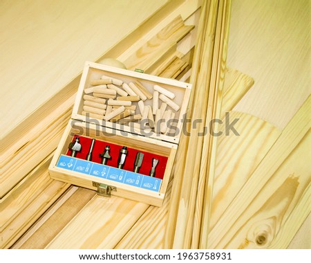 On a wooden background, close-up of wooden products are laid out, corners, glazing beads and a cashier next to it is a suitcase with a set of cutters for cutting wood.  Photo view from the top.