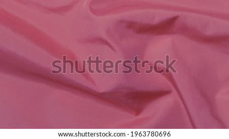 Pink background from crumpled, wavy fabric. Soft focus.
