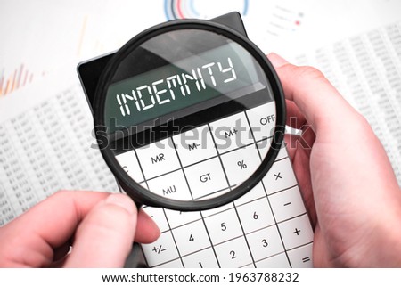 The word indemnity is written on the calculator. Business man holding a calculator in his hand. Royalty-Free Stock Photo #1963788232